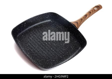 modern stylish kitchen grill pan Yes square shape with a dark non-stick coating and a corrugated bottom surface with a brown handle on a white Stock Photo