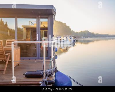 houseboat on a river in a early sunny morning. floating house is a pleasant place for rent for weekend Stock Photo