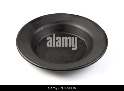 An old black soup plate on a white background. Stylized tableware. Side view. Stock Photo