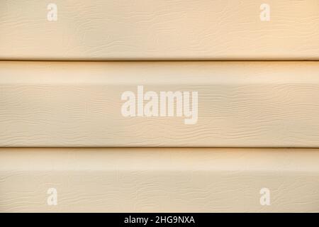 Textured beige siding background. Beige sheathing material for houses in close-up. Stock Photo