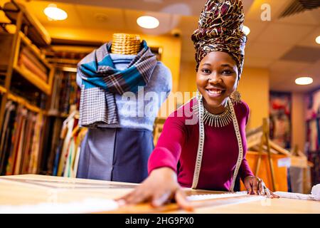 tanzanian woman with snake print turban over hear working in fabrics shop Stock Photo