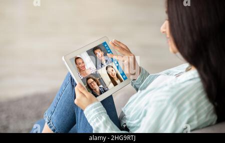 Middle-eastern woman having video conference with multiracial friends, using tablet Stock Photo