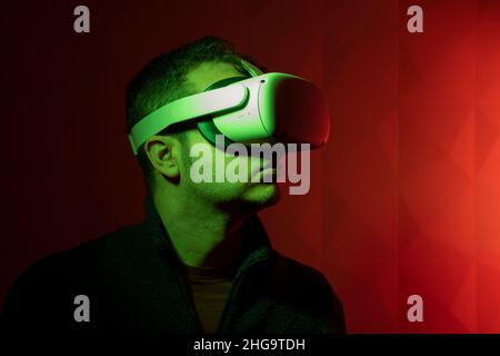 Man with white virtual reality goggles with red background and side green light Stock Photo