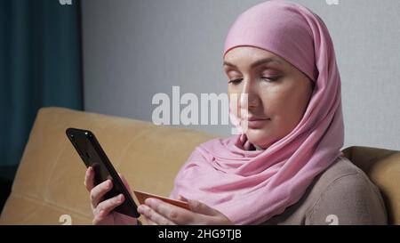 Young pregnant woman types phone number from business card Stock Photo