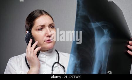 Orthopedist reports results of x-ray examination on phone Stock Photo