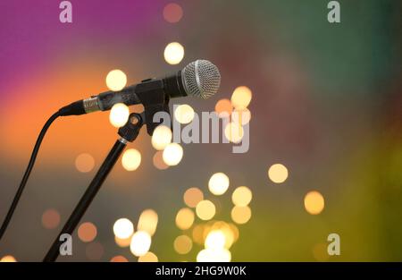 Stage retro microphone on a multicolored background in spots of golden bokeh. Stock Photo