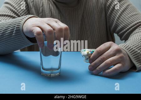 The man is holding a glass of water and pills. Stock Photo