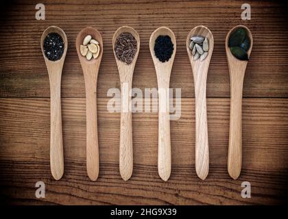 Set of organic seeds in spoons on wooden background, healthy natural food and nutrition concept Stock Photo