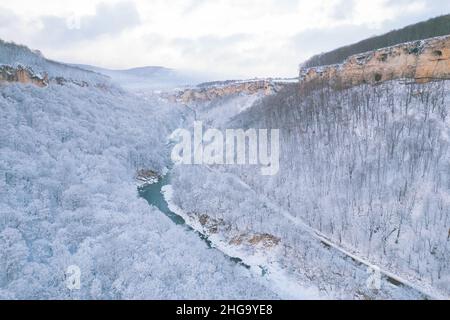 Aerial view of Plateau Lago-Naki mountain twisted road in the winter and driving car. Epic, snowy white winter and snow capped forest. Stock Photo