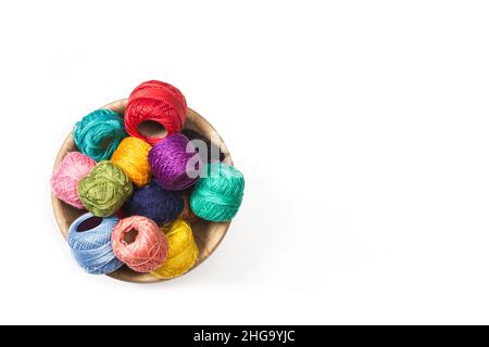Colored yarn spools in a wooden bowl on a white background with copy space Stock Photo