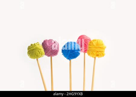 Colored wool balls on knitting needles on a white background Stock Photo