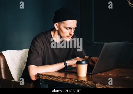 Young man mobile developer writes program code on a computer, programmer work in home office. Stock Photo