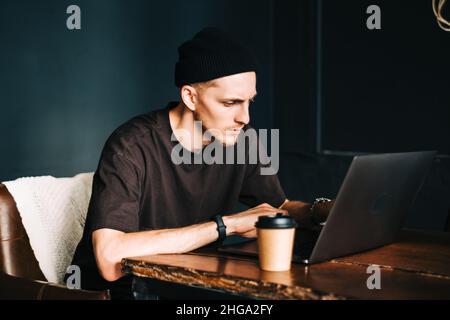 Young man mobile developer writes program code on a computer, programmer work in home office. Stock Photo