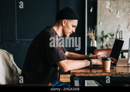Young man mobile developer writes program code on a computer, programmer work in home office. Stock Photo