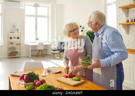 Happy mature couple helping each other while cooking healthy vegetable salad together Stock Photo