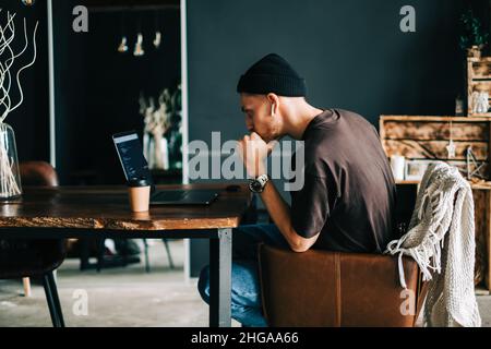 Young man mobile developer writes program code on a computer, programmer work in home office. Stock Photo