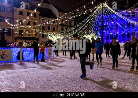 Warsaw, Poland - December 19, 2019: Old town market square rynek people skating at ice rink Warszawa at night with Christmas illumination decorations Stock Photo
