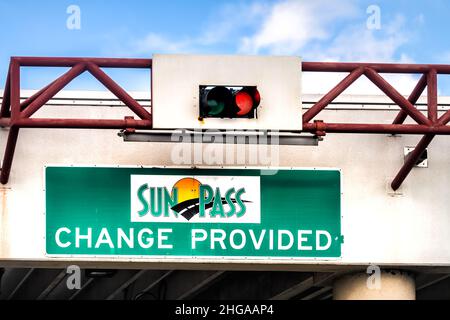 Miami, USA - August 5, 2021: Green sign for SunPass toll Sun Pass change provided text with red light on i-75 road street highway from Miami Ft Lauder Stock Photo