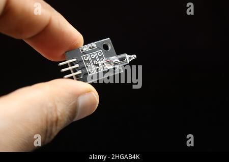 Mercury tilt switch sensor module held in hand isolated on black background, Electronic sensors for microcontrollers Stock Photo