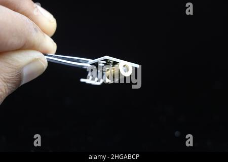 Closeup view of laser module with copper casing isolated on black background held in hand Stock Photo