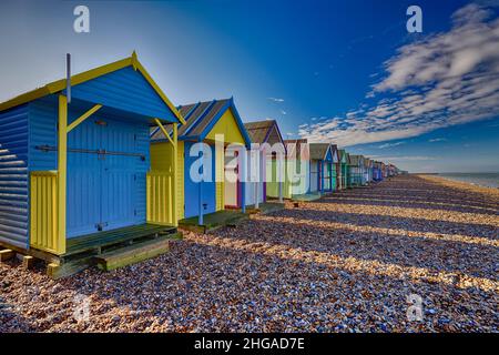 Row of Colourful Beach Huts on the pebble beach at Herne Bay in Kent UK Stock Photo