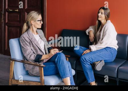 The conversation of a female psychotherapist with a female patient in the office during the session. Stock Photo