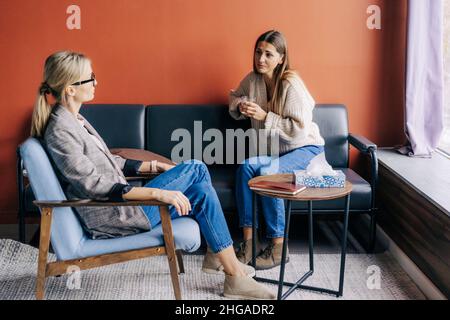 Female psychologist listening to a depressed woman in an appointment. Stock Photo