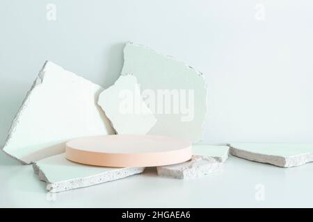 Broken plaster concrete stone pieces and empty round beige platform podium for cosmetics or products on white background. Front view Stock Photo