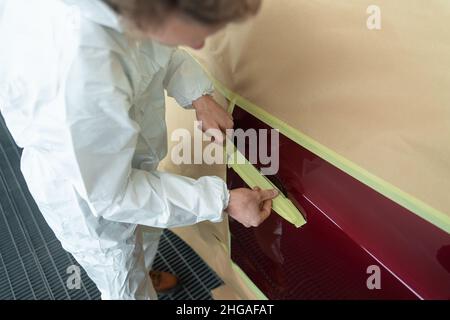Closeup view of auto painter's hands who masking a car
