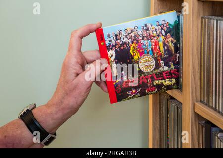 A CD of Sgt Peppers Lonely Heart Club Band by The Beatles being removed from a rack. It was the 8th studio album by The Beatles, released in 1967. Stock Photo