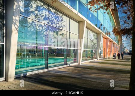 People walk past the international swimming pool at Corby, England, on a sunny winter day. Stock Photo