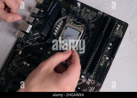 Engineer plugging CPU microprocessor to motherboard socket. Computer technology hardware maintenance or repair.  Electronics Development Working on Co Stock Photo