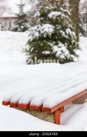 Bench in a park covered completely by snow after heavy snowfall Stock Photo
