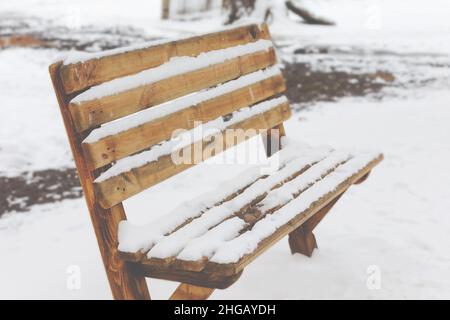 Bench in a park covered completely by snow after heavy snowfall Stock Photo