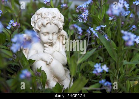 White little angel figurine in a flower bed Stock Photo