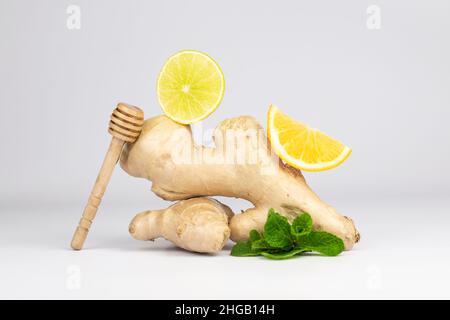 Ginger root, lemons slices, green fresh mint and honey stick. Food balance and detox concept composition. Stock Photo