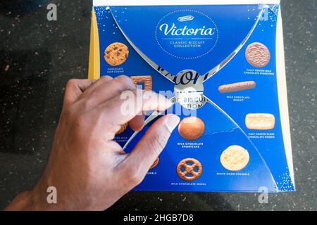 Adult Asian male opening McVities Victoria biscuit selection Stock Photo