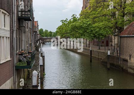 Water canal between houses in the city of Dordrecht in Holland. In the background is a stone bridge. Stock Photo