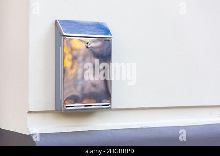 Stainless steel metal mailbox on the white wall of the house Stock Photo