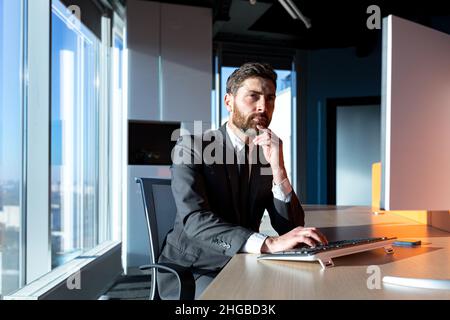 thinking male businessman working at computer in modern office by the window Stock Photo