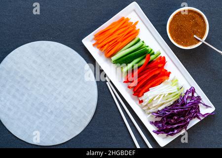 Ingredients for vegan vietnamese spring rolls with carrot, cucumber, red cabbage, spring onions and spicy sauce. Healthy eating Stock Photo