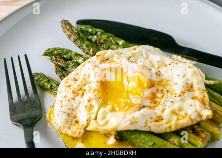 An exquisite cooked asparagus prepared with a fried egg, seasoned and spiced. Natural cuisine, Gourmet. Stock Photo