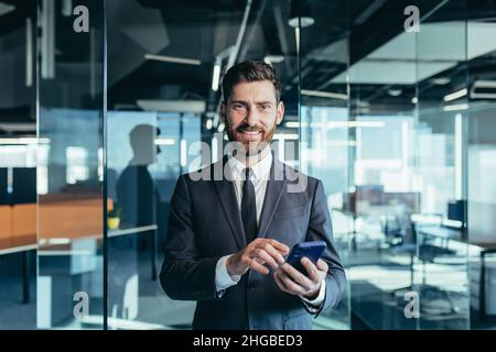 Happy and smiling businessman having fun using phone, typing messages on phone, smiling and looking at camera, close-up portrait Stock Photo