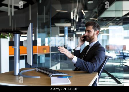 Serious and thoughtful male entrepreneur working in the office at the computer in a business suit Stock Photo