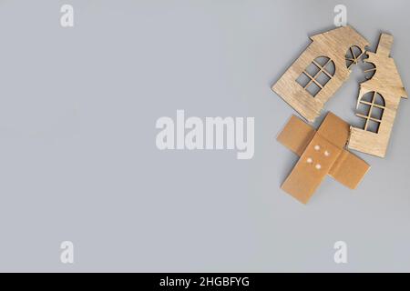 Closeup of broken house figure with crossed band aid on grey background top view, copy space, divorce, relationship problems, moving house, mortgage, Stock Photo