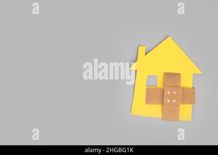 Closeup of broken house figure with crossed band aid on grey background top view, copy space, divorce, relationship problems, moving house, mortgage, Stock Photo