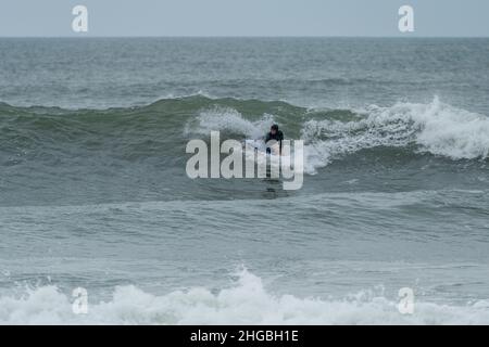 Ocean Wave Trick Roping Bodyboarder performing a 360 trick surfing ocean wave on a cloudy ...
