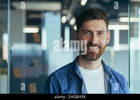 Successful businessman with beard smiling and looking at camera happy, close up photo, in modern office Stock Photo
