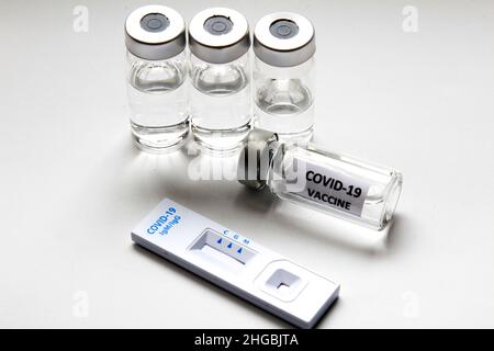 Rapid Antigen Diagnostic Test cassette of Coronavirus SARS-CoV-2 Covid-19 and vials with vaccine on white background Stock Photo