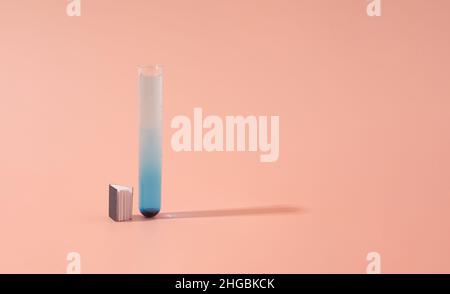 Miniature book and test tube containing blue liquid on a pastel pink background. Scientific research minimal concept. Stock Photo